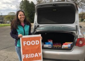 Community member Christy Fieldsa displays a sign during a recent "Food Friday" at The Factory Ministries. (Photo provided by The Factory Ministries)