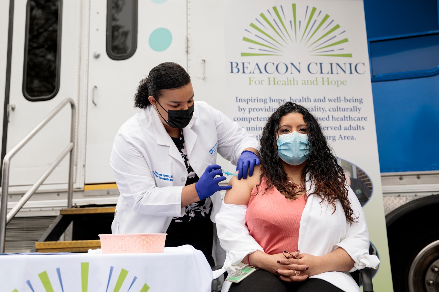 Luz Colon, right, executive director of the Pa. Advisory Commission on Latino Affairs, receives a Covid-19 vaccine from Penn State Health System clinician Dr. Sarah Ramirez at the end of a press conference,  outside Beacon Clinic in Harrisburg on Monday, April 12, 2021. Colon received the vaccine publicly to demonstrate confidence in its safety and efficacy. 