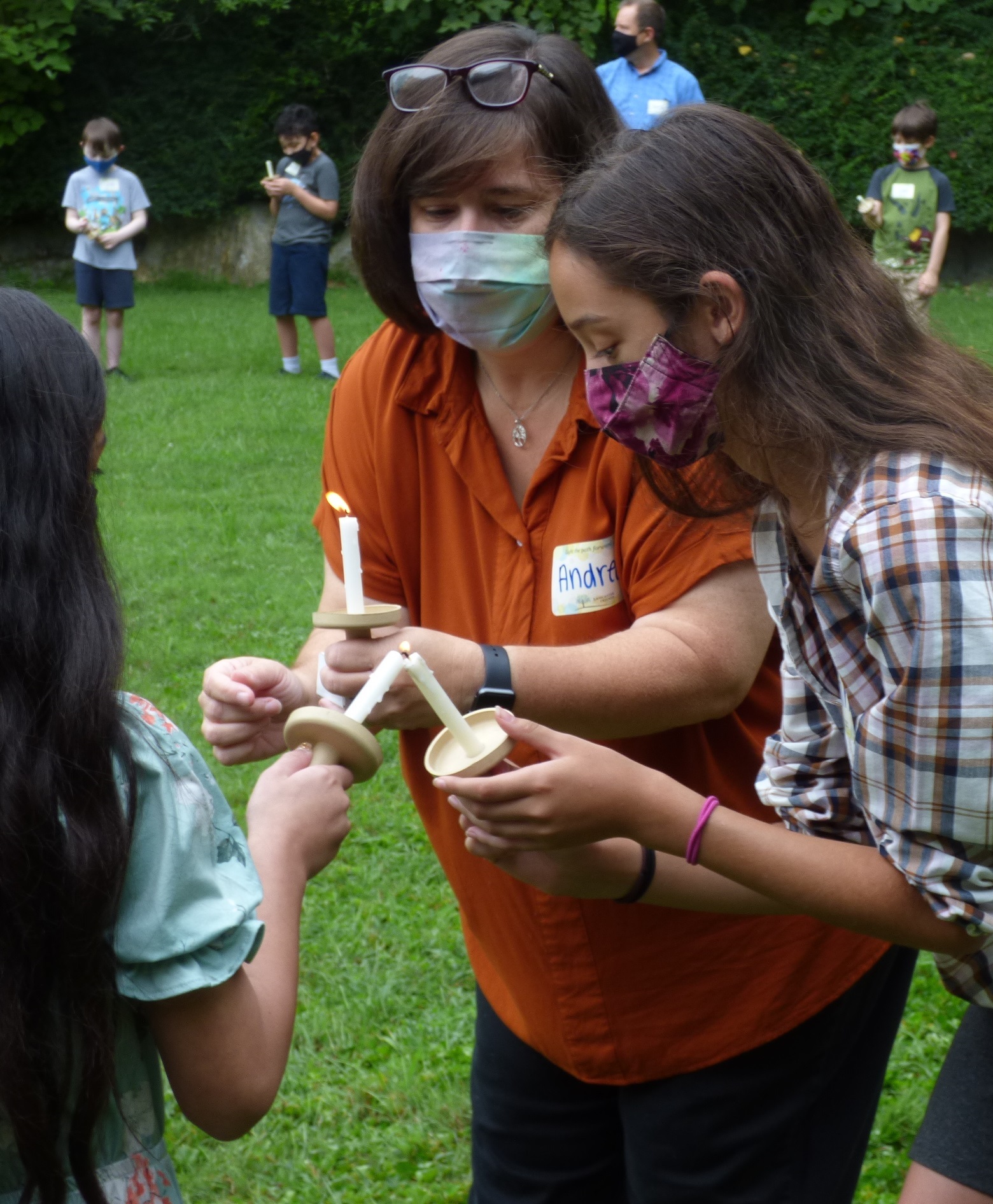 Andrea Paz y Miño Carty, in orange blouse, helps students light their candles during the opening ceremony for Lancaster Friends School on Monday, Aug. 30, 2021. (Photo: Tim Stuhldreher) 