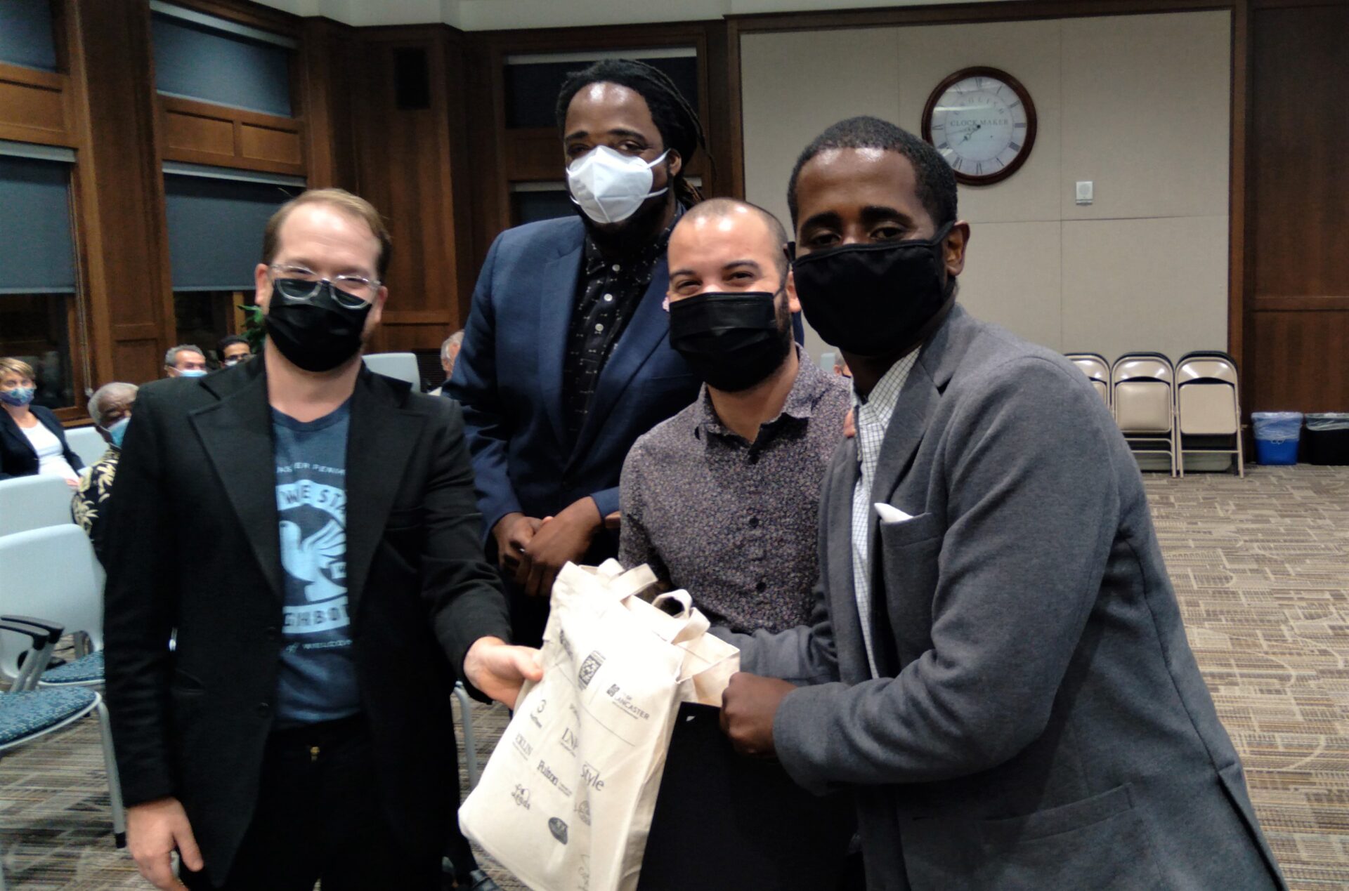 Showing off a tote bag containing welcome materials for resettled immigrants in Lancaster city are, from left, Matt Johnson of Church World Service; City Council President Ismail Smith-Wade-El; Councilman Xavier Garcia-Molina and community activist Ahmed Ahmed. (Photo: Tim Stuhldreher) 